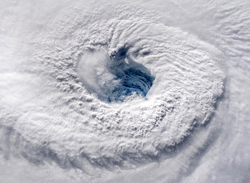 L'oeil d'une tempête vue d'en haut, dans lequel on devine des sommets enneigés.